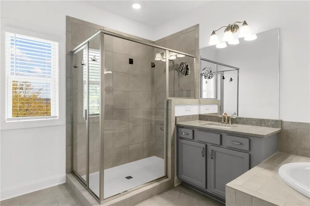 Bathroom with vanity, a stall shower, light tile patterned flooring, and a bath