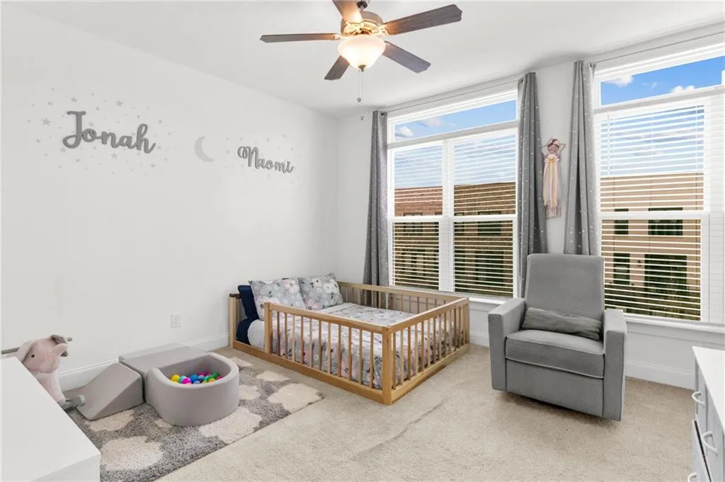 Bedroom with a nursery area, carpet floors, and ceiling fan