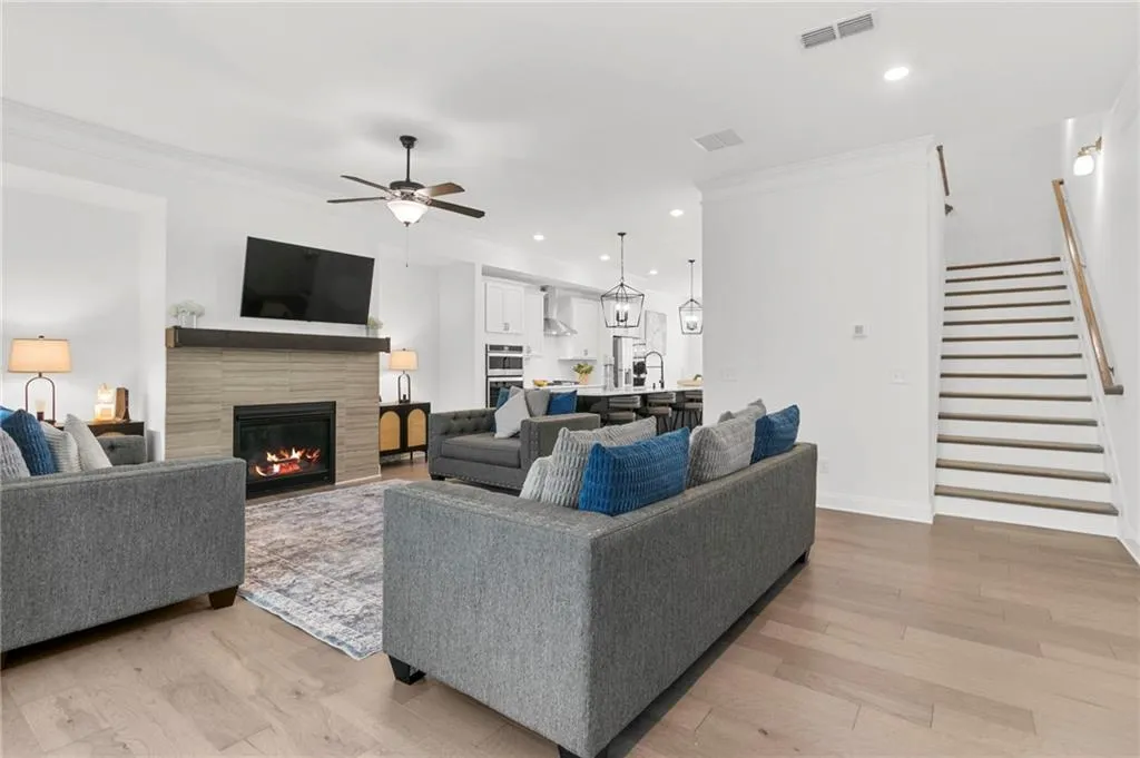 Living area with light wood-style floors, crown molding, a fireplace, ceiling fan, and recessed lighting