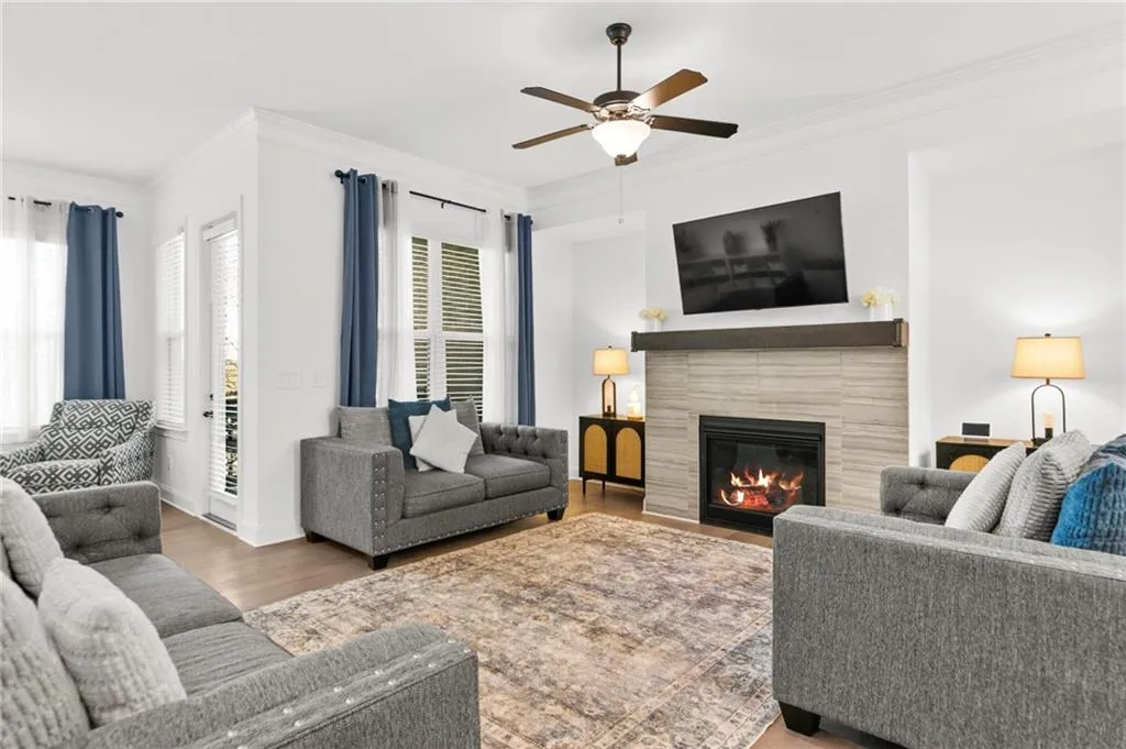 Living room with ornamental molding, wood finished floors, a ceiling fan, and a fireplace