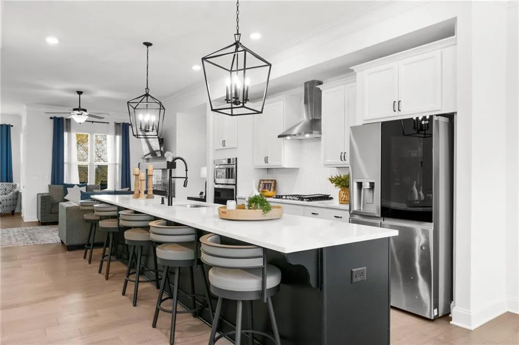 Kitchen featuring stainless steel appliances, a kitchen bar, a large island with sink, a ceiling fan, and crown molding