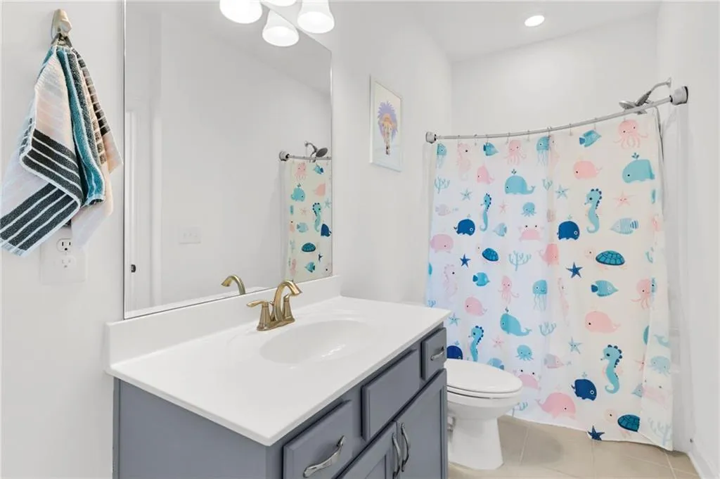 Full bathroom with vanity, light tile patterned floors, a shower with shower curtain, and recessed lighting