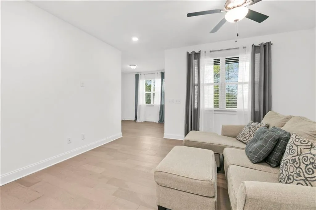 Living room with a ceiling fan, light wood finished floors, and recessed lighting