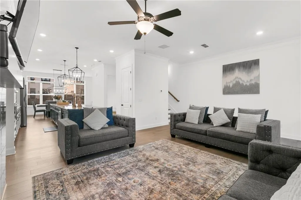 Living area with crown molding, ceiling fan, light wood finished floors, and suspended lighting