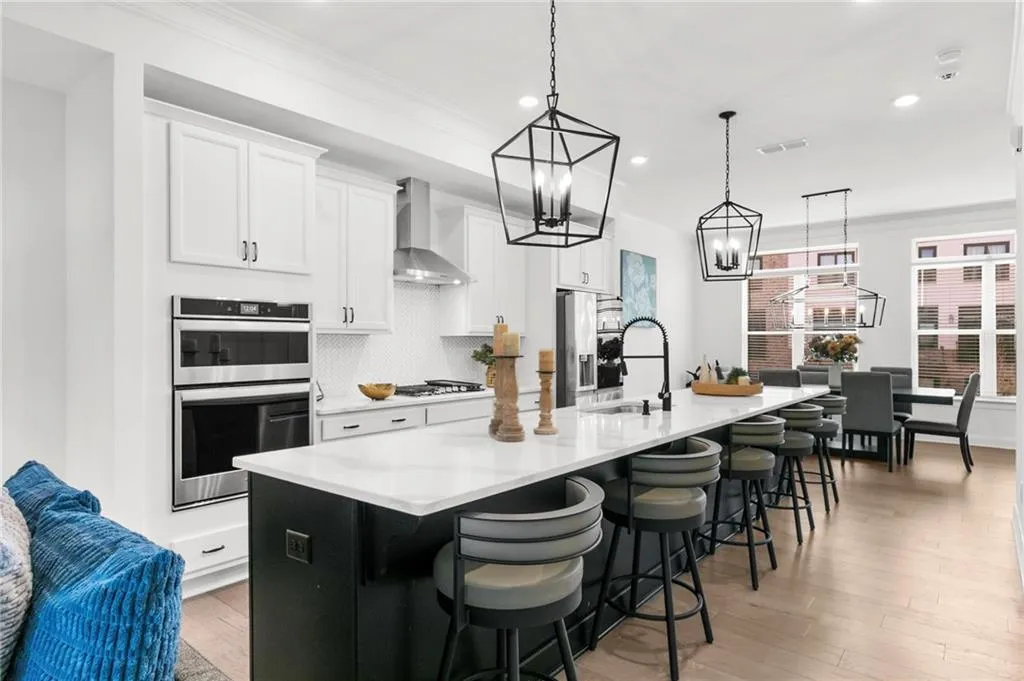 Kitchen featuring ornamental molding, a large island with sink, two tone cabinets, stainless steel appliances, and a breakfast bar area