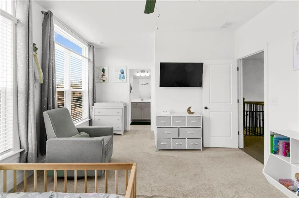 Bedroom featuring light carpet, ensuite bathroom, and ceiling fan
