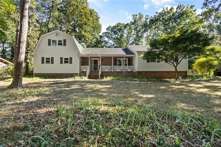 Gabled home exterior featuring light-colored siding, dark shutters, and a covered porch with white railings