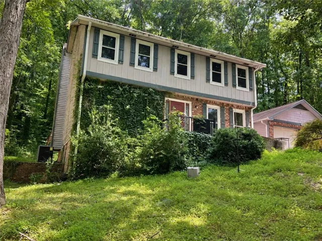 Two-story residence featuring a brick and siding exterior, multiple windows with shutters, and a front porch