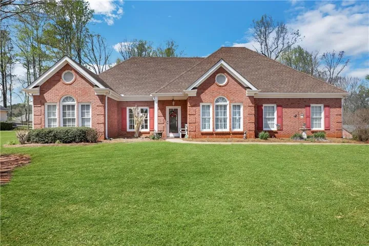 Brick exterior with a shingled roof, white trim, and red shutters