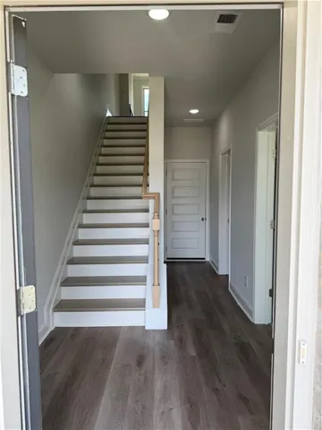 Inviting entryway featuring a staircase with wood-finish treads and white risers, complemented by wood-finish flooring