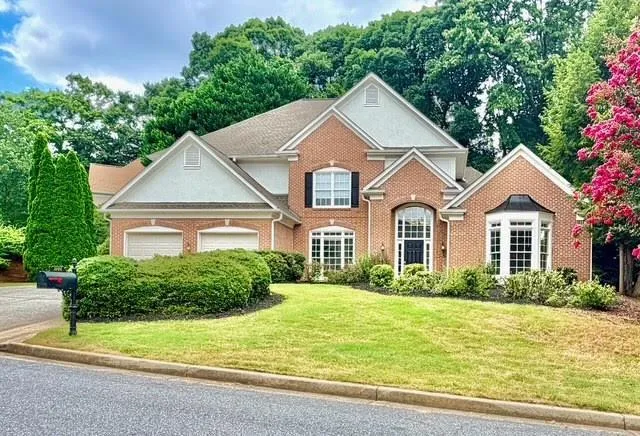 Brick exterior featuring a two-car garage and a combination of arch-top and bay windows