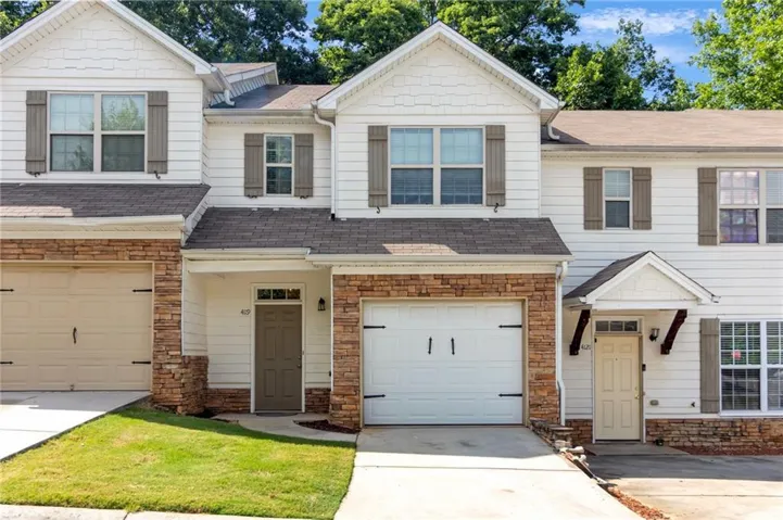 Exterior featuring stone accents, white siding, a single-car garage, and shuttered windows
