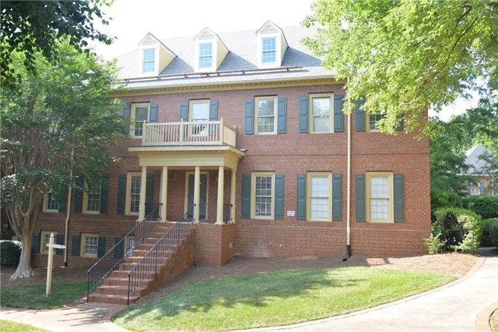 Brick exterior with a prominent two-story entry featuring a columned portico and an upper-level balcony
