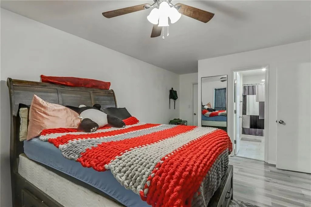 Bedroom featuring wood finished floors, ceiling fan, and ensuite bath Bedroom featuring wood finished floors, ceiling fan, and ensuite bath