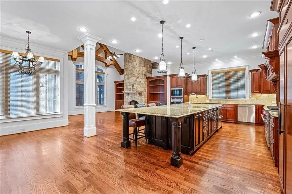 Kitchen featuring a breakfast bar, an inviting chandelier, hardwood / wood-style flooring, tasteful backsplash, and a kitchen island with sink