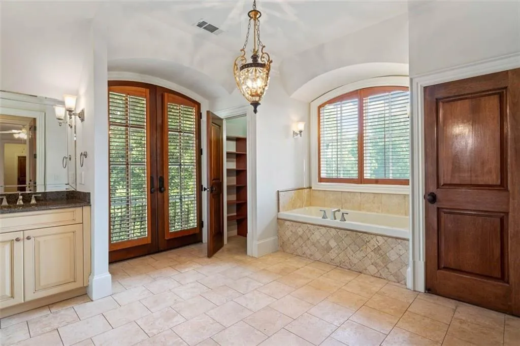 Bathroom with french doors, vanity, tiled bath, and tile floors