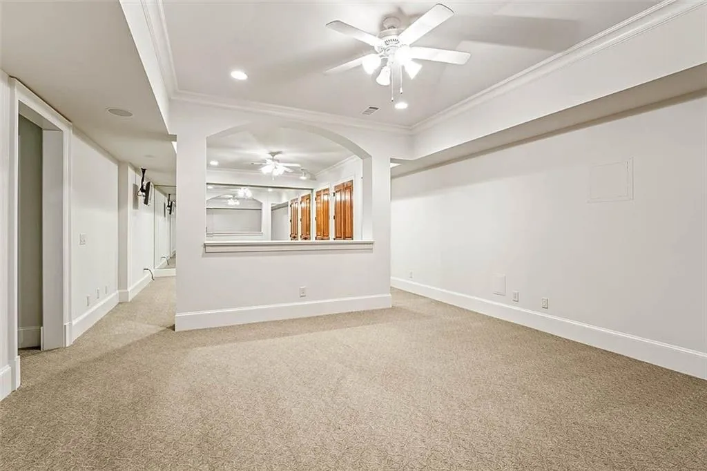 Unfurnished living room featuring crown molding, light carpet, and ceiling fan