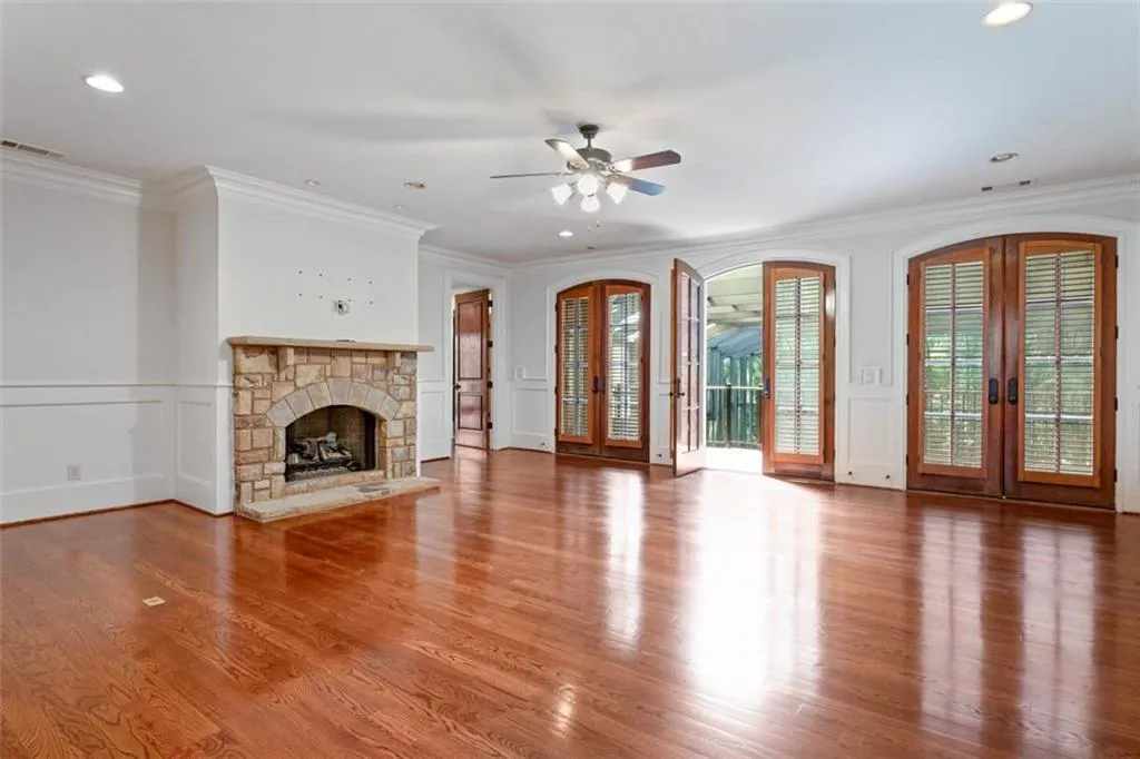 Unfurnished living room with a stone fireplace, crown molding, and hardwood / wood-style flooring