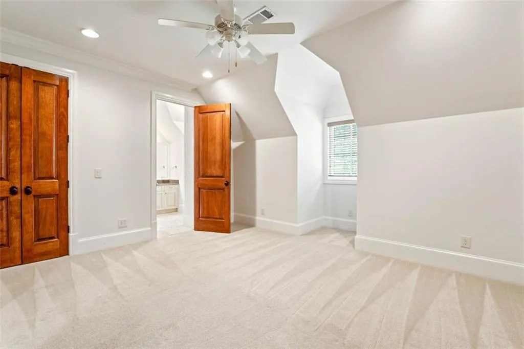 Bonus room featuring vaulted ceiling, light colored carpet, and ceiling fan