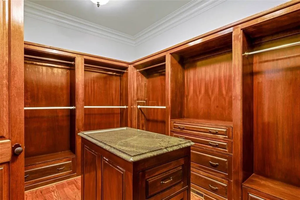 Walk in closet with light hardwood / wood-style floors