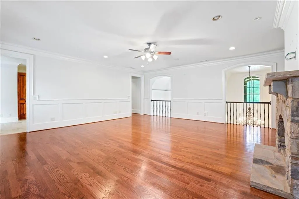 Upstairs family room with wood flooring, crown molding, ceiling fan, and a fireplace