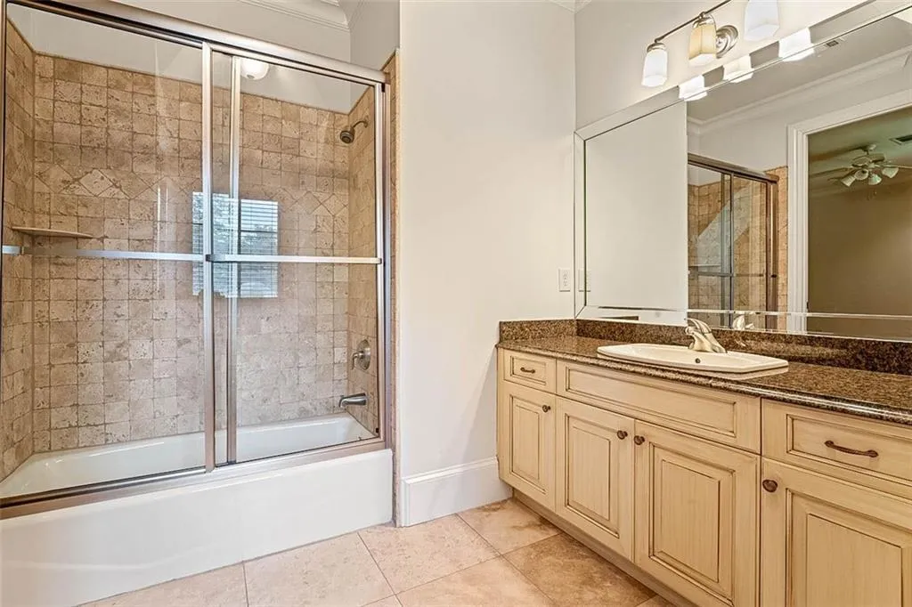 Bathroom with vanity, ornamental molding, tile flooring, ceiling fan, and combined bath / shower with glass door
