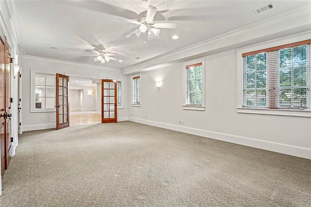 Spare room featuring french doors, ornamental molding, and light colored carpet
