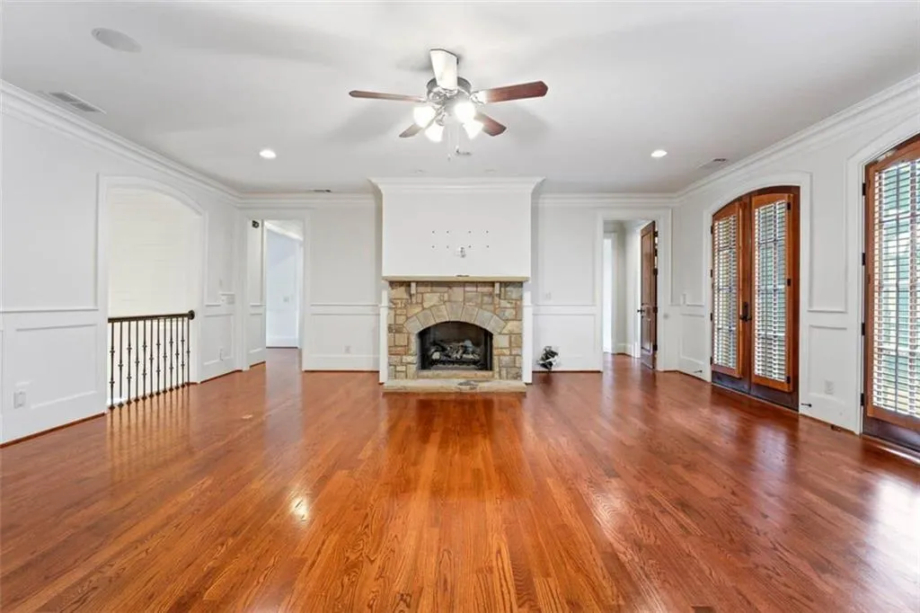 Unfurnished living room featuring ceiling fan, plenty of natural light, a fireplace, and dark hardwood / wood-style flooring