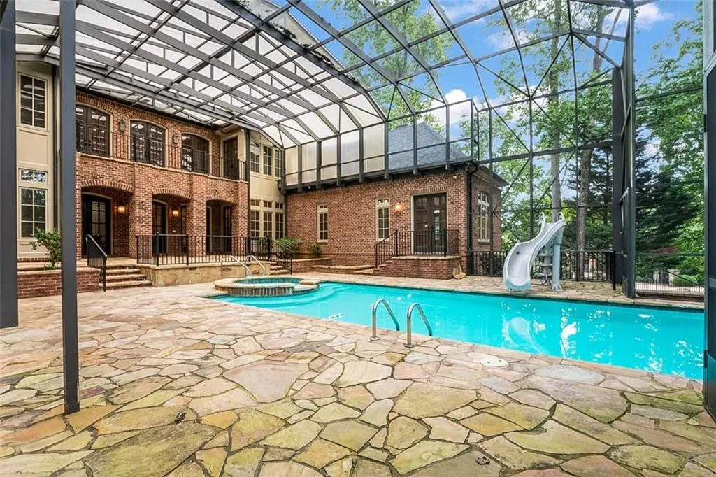 View of swimming pool with an in ground hot tub and a water slide