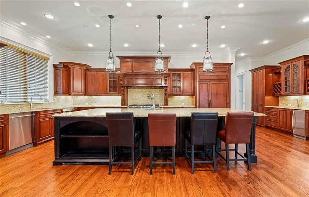 Kitchen with light hardwood / wood-style flooring, a kitchen island with sink, pendant lighting, and dishwasher