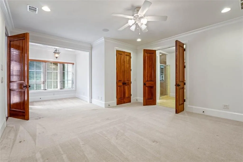 Empty room featuring ornamental molding, light carpet, and ceiling fan
