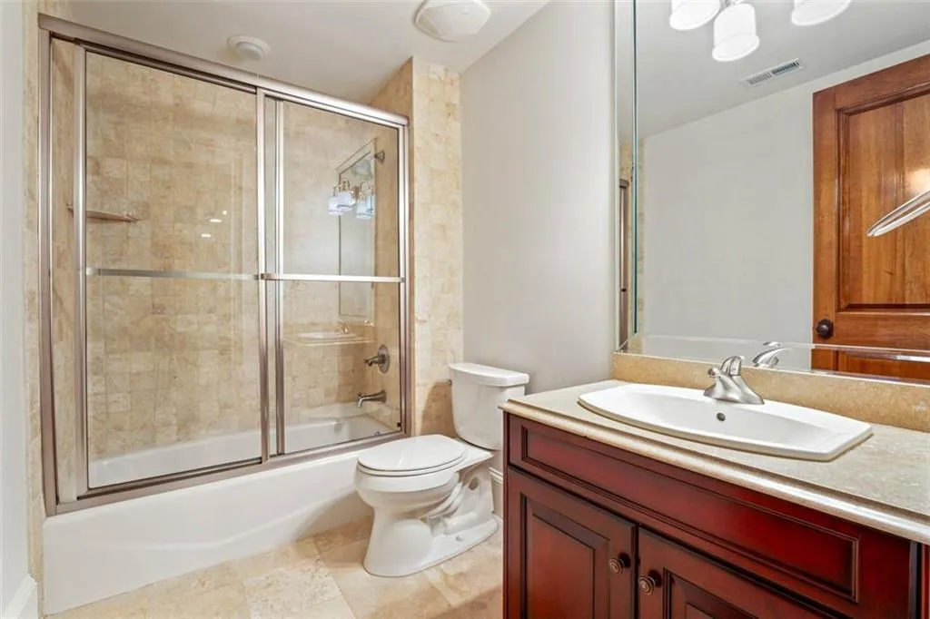 Full bathroom with tile floors, enclosed tub / shower combo, vanity, and toilet