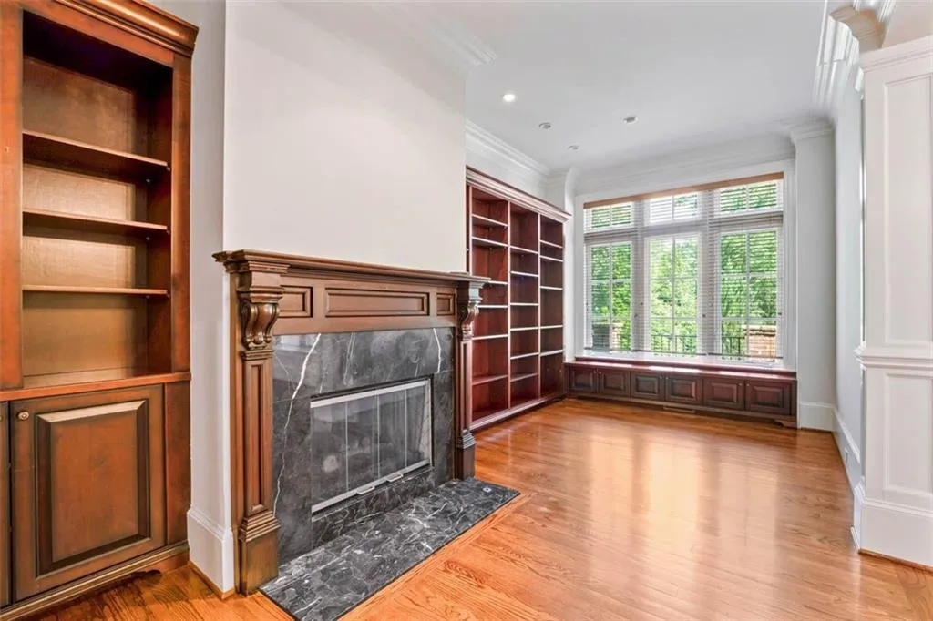 Unfurnished living room featuring a high end fireplace, crown molding, light wood-type flooring, and built in features