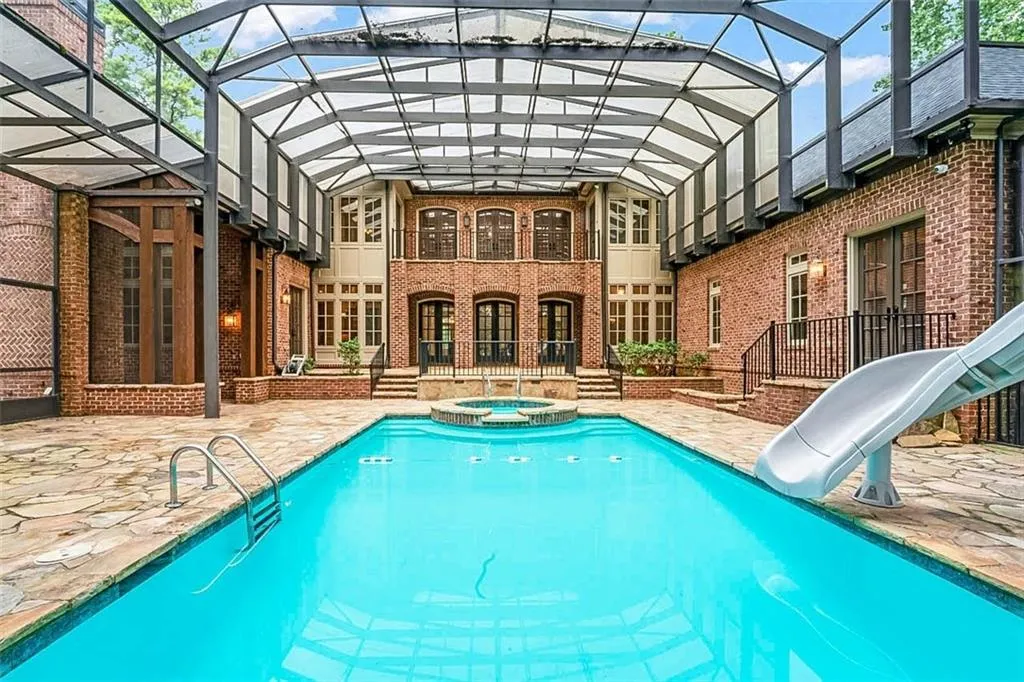 View of swimming pool featuring a patio, glass enclosure, an in ground hot tub, and a water slide