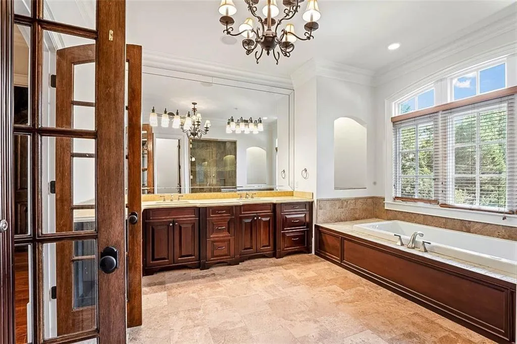 Bathroom with tile floors, an inviting chandelier, a washtub, and oversized vanity