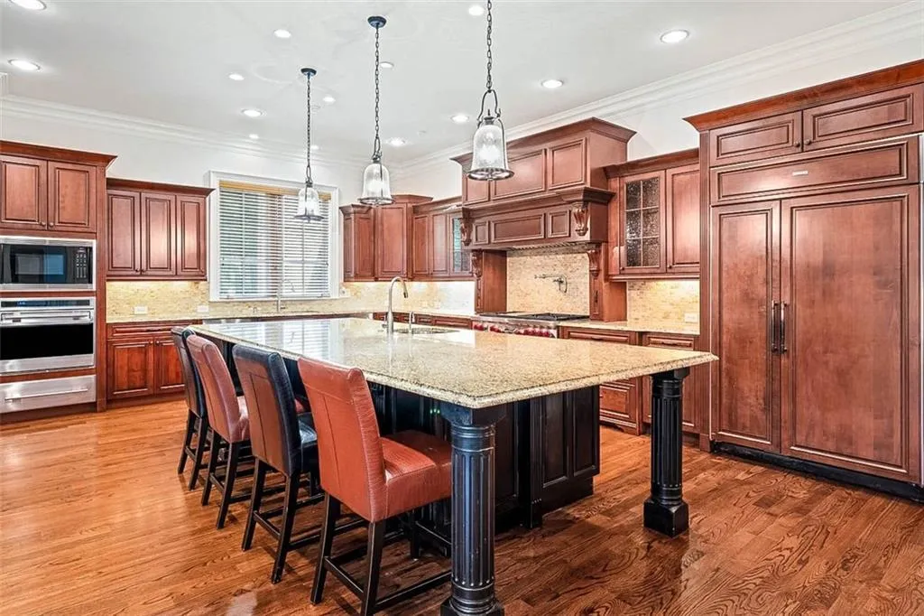 Kitchen featuring tasteful backsplash, a breakfast bar, built in appliances, and dark hardwood / wood-style floors