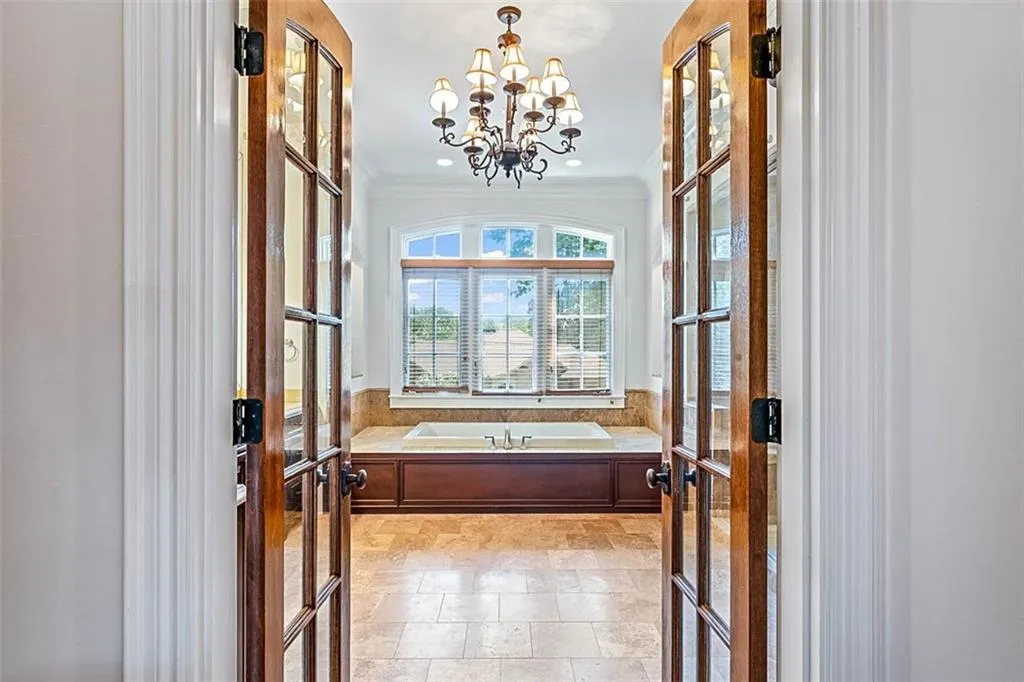 Tiled foyer entrance featuring an inviting chandelier, ornamental molding, and french doors