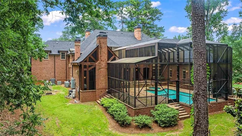 Rear view of property featuring a lawn and glass enclosure