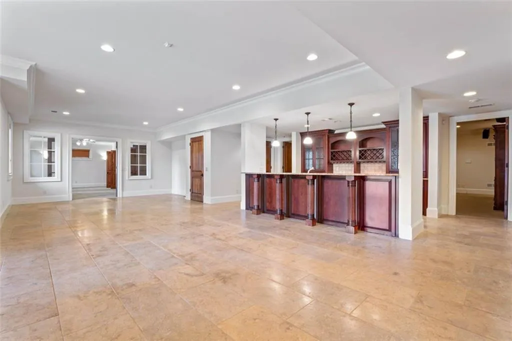basement entertaining room with ornamental molding and light tile flooring