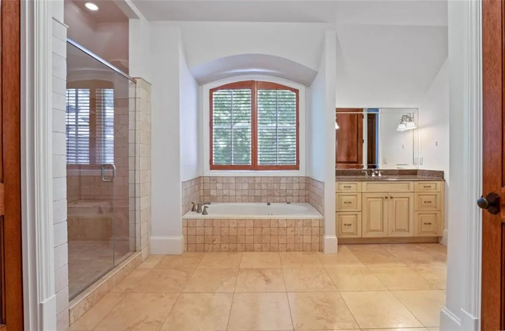 Bathroom featuring tile floors, plus walk in shower, and vanity with extensive cabinet space