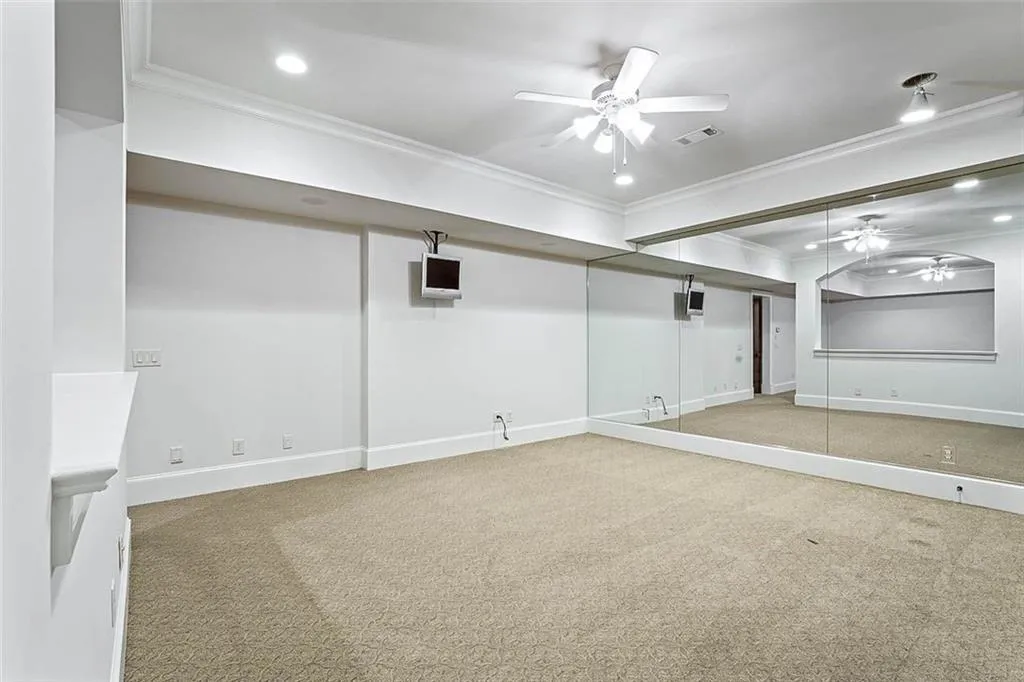 Carpeted empty room featuring ornamental molding and ceiling fan