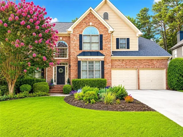 Stunning two-story brick colonial featuring a welcoming front elevation with arched entry, black shutters, and distinctive gable roofline