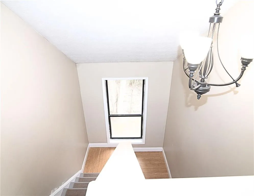 Staircase featuring hanging lights and wood finished floors