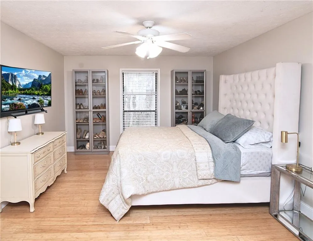 Bedroom featuring light wood-style floors, a ceiling fan, and a textured ceiling