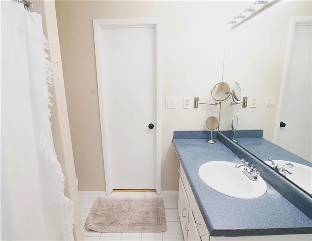 Full bath featuring vanity, a shower with curtain, and light tile patterned flooring