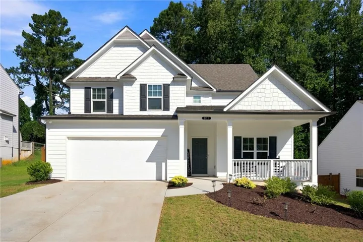 Classic two-story home featuring white fiber cement siding, a welcoming front porch with white railings, and a two-car garage