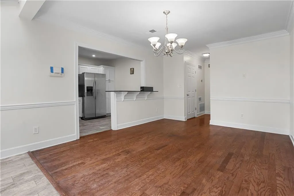 Unfurnished dining area featuring crown molding, dark wood-type flooring, and a chandelier