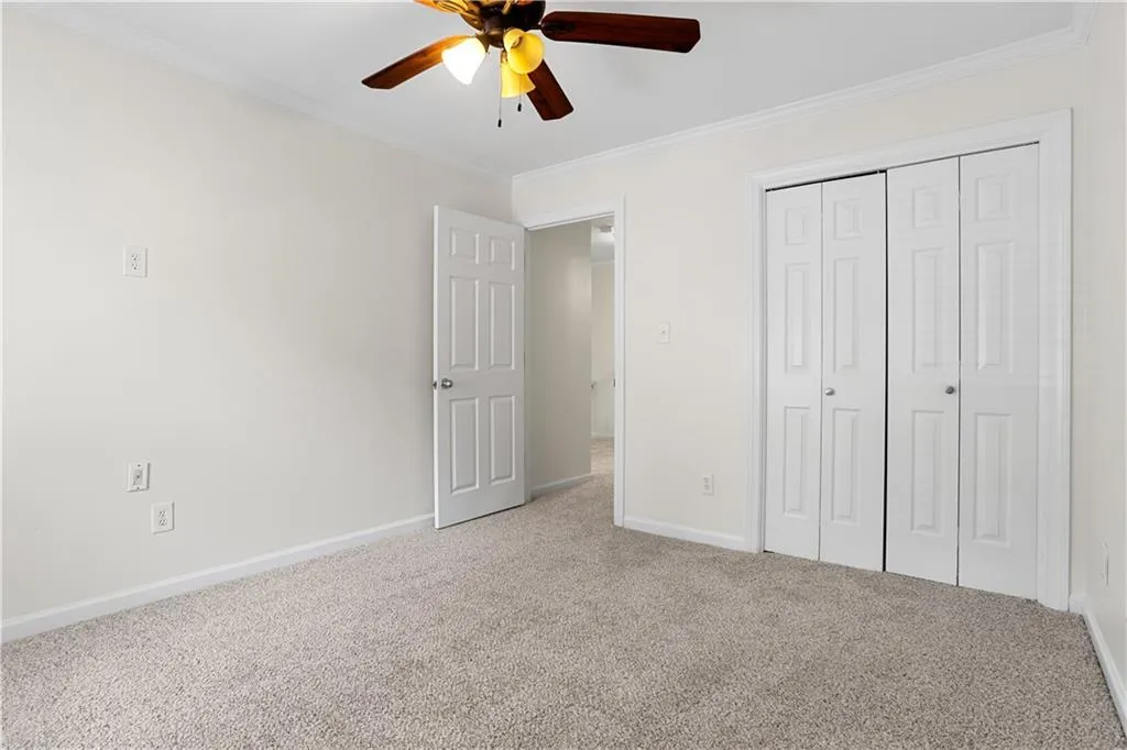 Unfurnished bedroom with crown molding, carpet, a closet, and ceiling fan