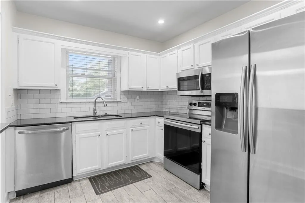 Kitchen with stainless steel appliances, tasteful backsplash, white cabinetry, wood finish floors, and recessed lighting