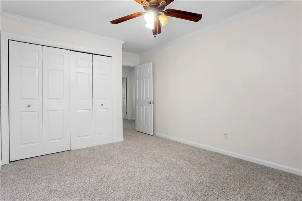 Unfurnished bedroom featuring carpet, ornamental molding, a closet, and ceiling fan